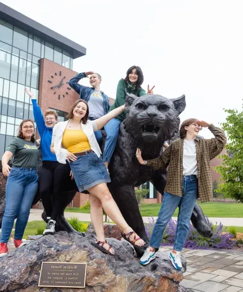 五名学生站在新大校园里的野猫雕像前
