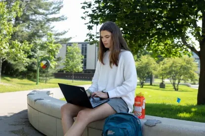 买球app学生坐在外面使用笔记本电脑.